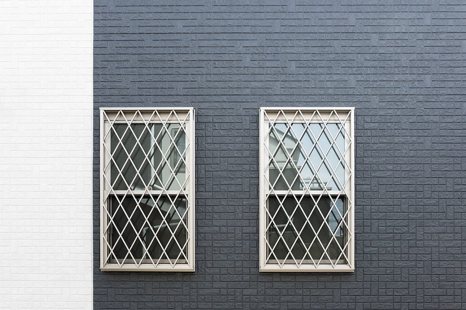 住宅の外壁建材の面格子窓とサイディング白とグレー